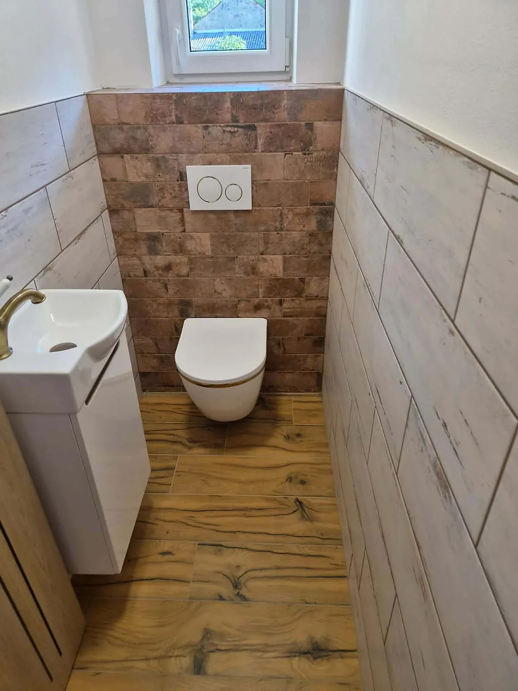 WC se závěsnou mísou, cihlovým obkladem za ní a umyvadlem na skříňce