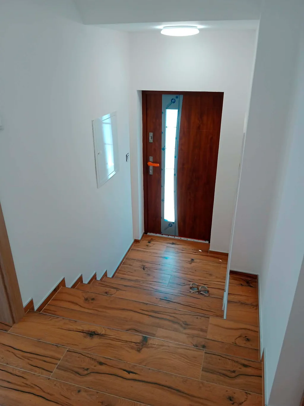 Zádveří se vstupními dveřmi a schodem obloženým dlažbou