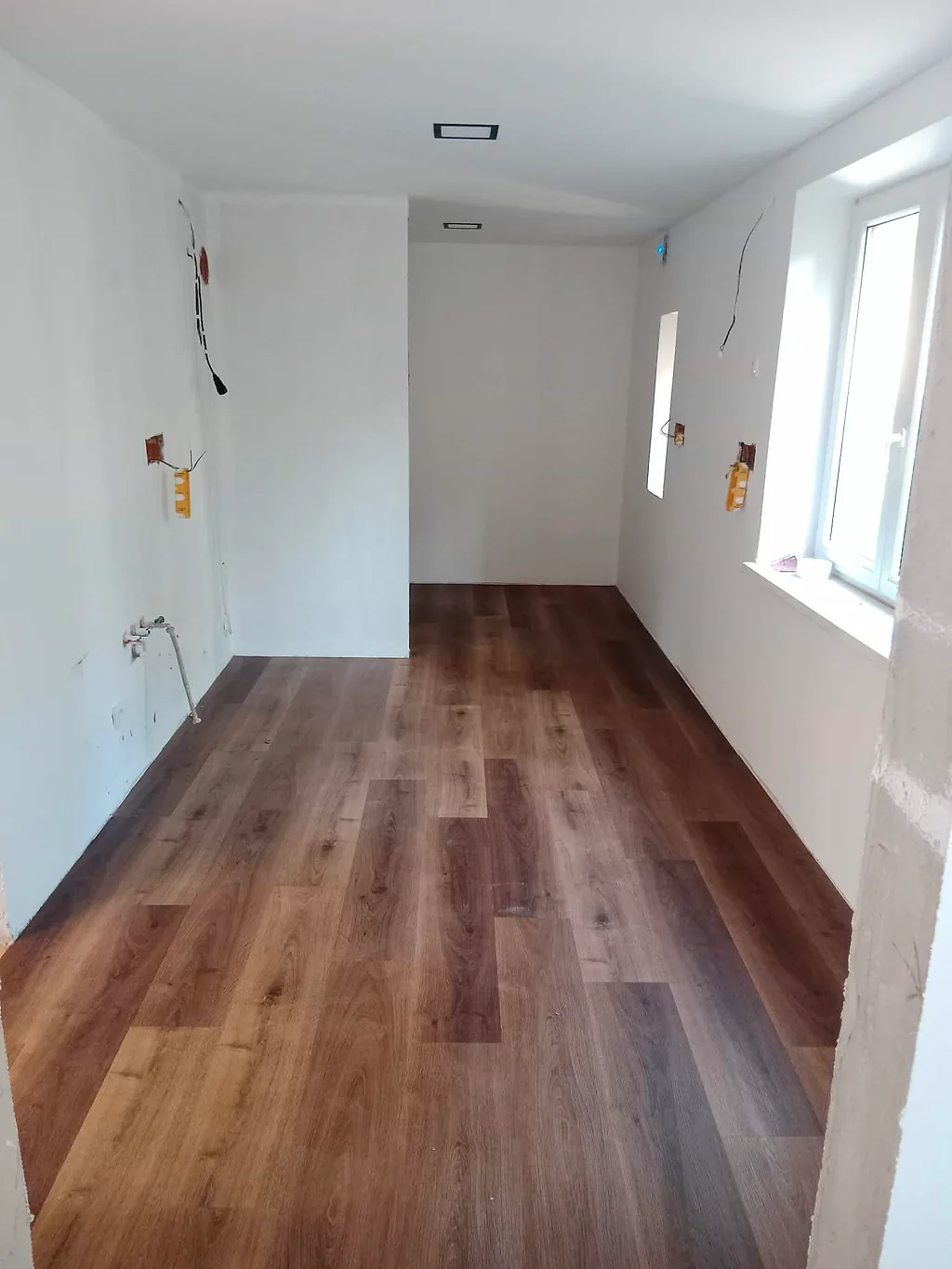Místnost s novou vinylovou podlahou a připravenou elektroinstalací