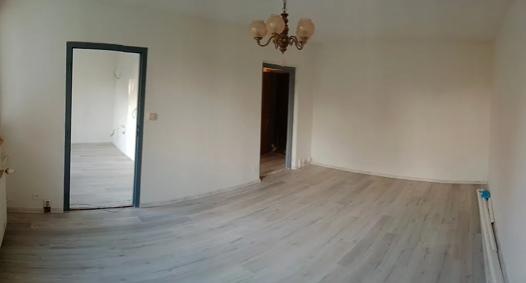 Hotový pokoj po rekonstrukci s novou plovoucí podlahou a bílými stěnami