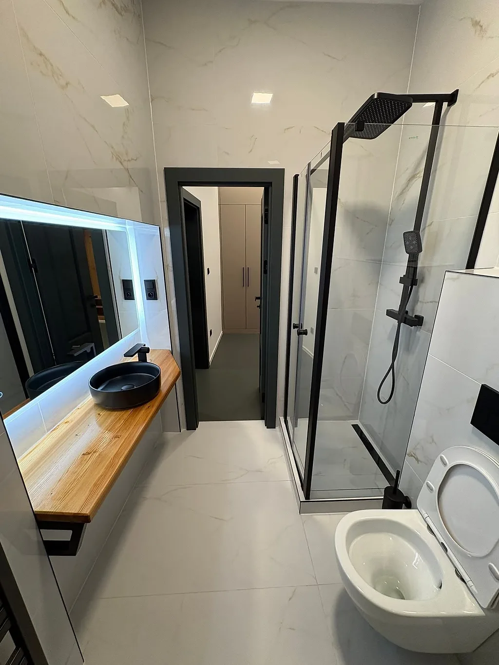Mramorová koupelna se sprchovým koutem v černém rámu a závěsným WC