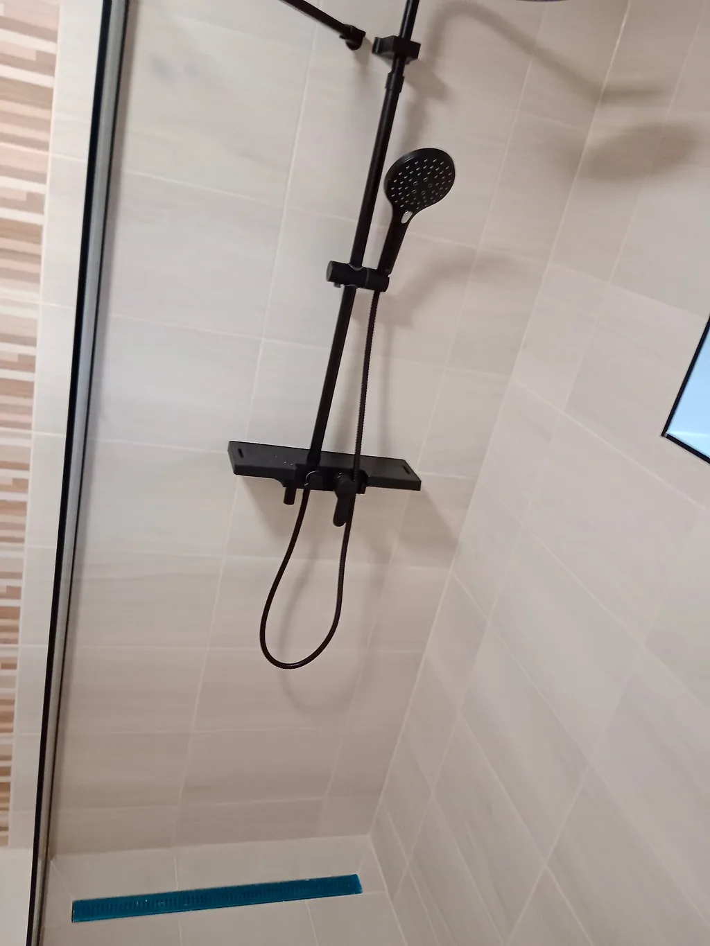 Sprchový kout s černou baterií, skleněnou zástěnou a odtokovým žlabem v podlaze